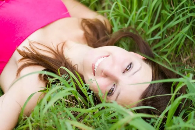 Woman laying in grass smiling