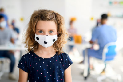 A girl, around 10 years old, wears a reusable mask.