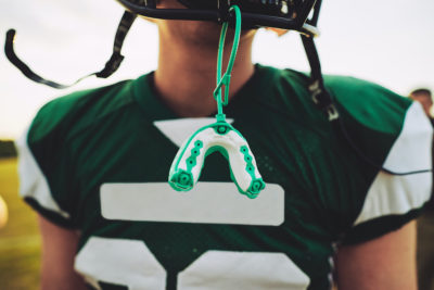 Closeup of a mouthguard hanging off the helmet of a football player