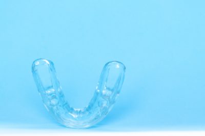 An image of a silicone dental mouthguard on a blue background.